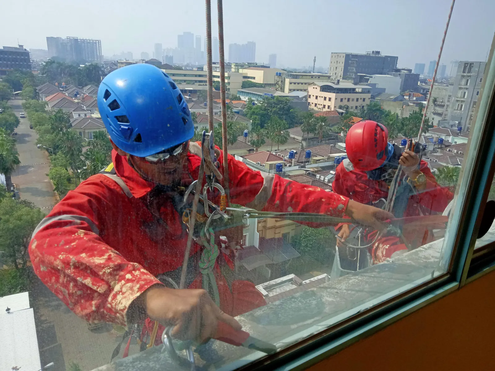 Tim teknisi bekerja pada area kaca gedung